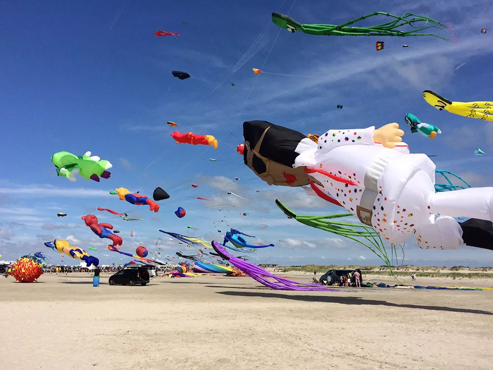 Strand mit bunten Drachen in der Luft