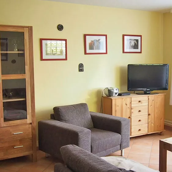 Wohnbereich Ferienwohnung 4 – Sessel, Fernseher, Sideboard und Schrank für 6 Personen