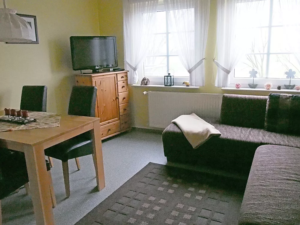 Wohnzimmer Ferienwohnung 2 – Couchecke, Esstisch und Fernseher