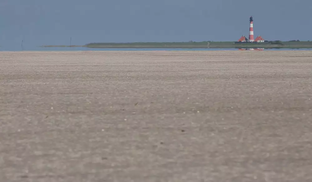 Endlos weiter Strand mit Blick auf den Leuchtturm Westerhever