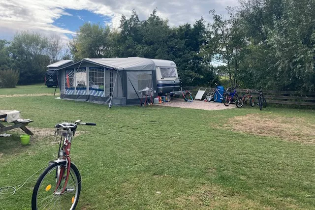 Campinganhänger mit Vorzelt und Fahrrädern auf dem naturnahen Campingplatz